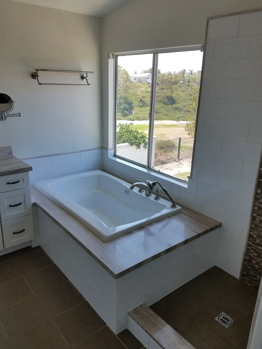 Drop-in soaking tub with tiled deck and hillside view