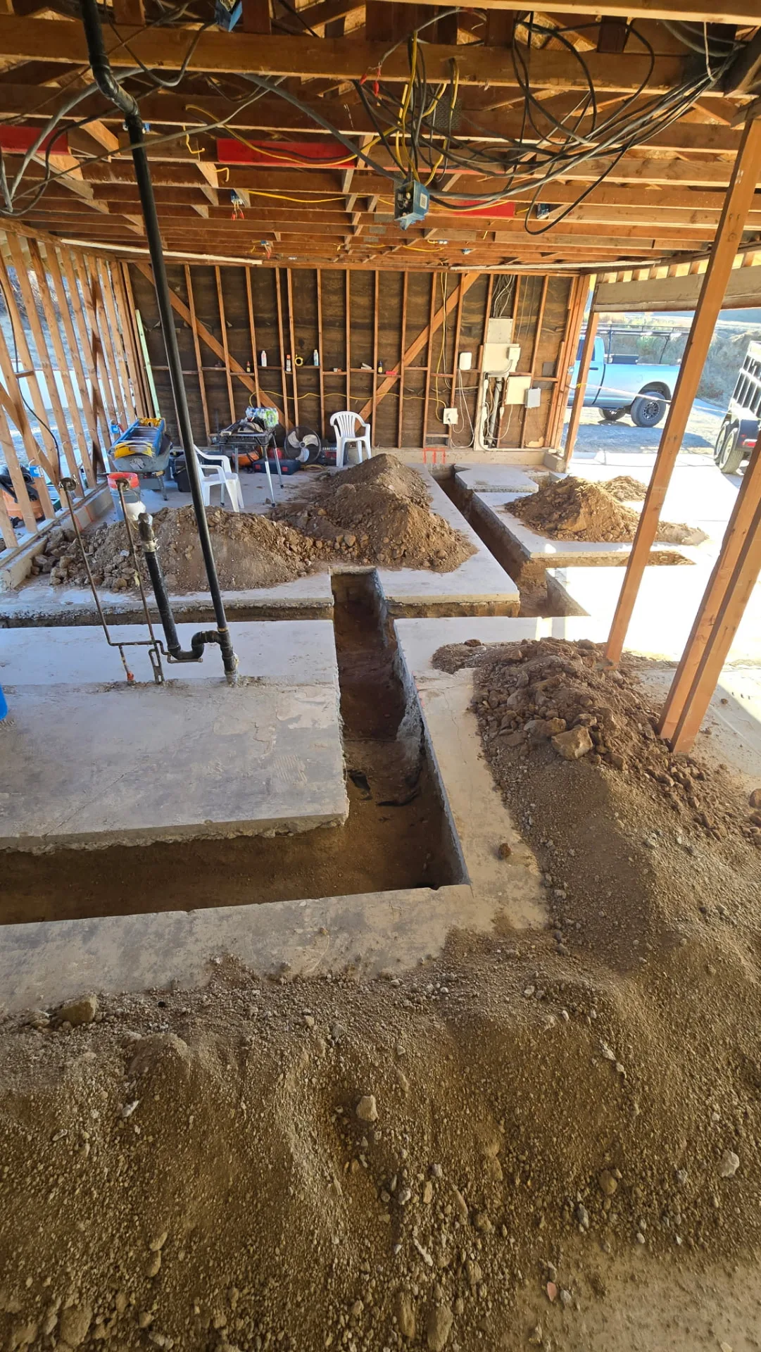 Murrieta construction interior with exposed wall studs, ceiling joists, electrical wiring, plumbing pipes and trenches cut into the concrete floor